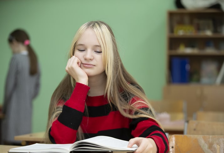 Student struggles with 6th grade reading skills in the library.