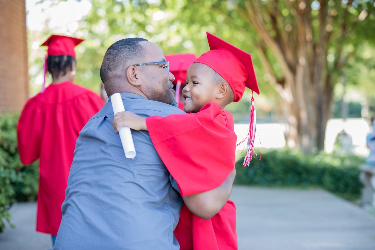 Father hugs son at his kindergarten graduation.